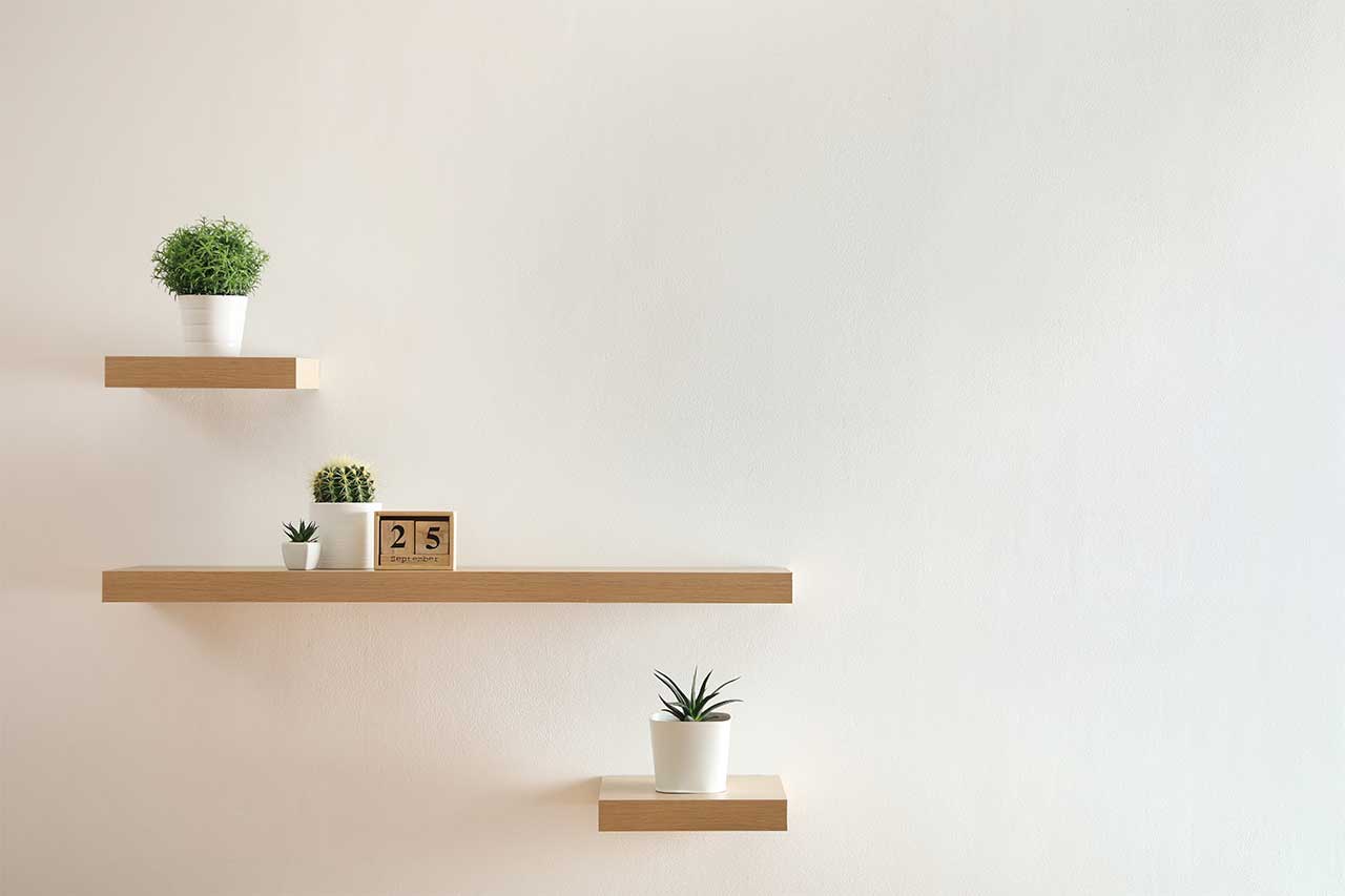 Wooden Shelves With Beautiful Plants And Calendar On Light Wall